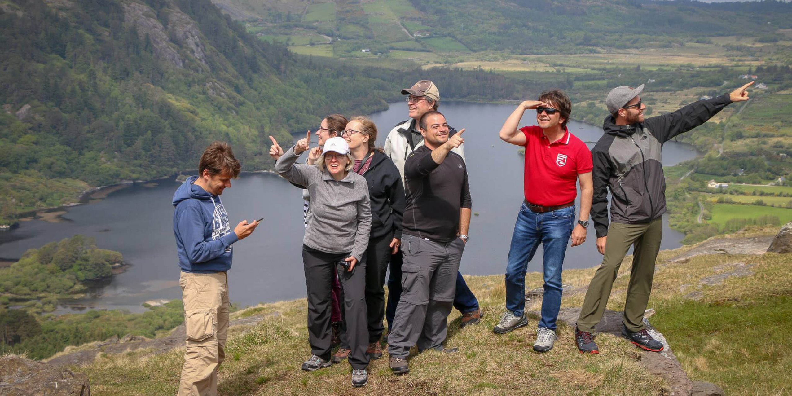 A silly Vagabond tour group pointing in different directions at Ladies View in Ireland
