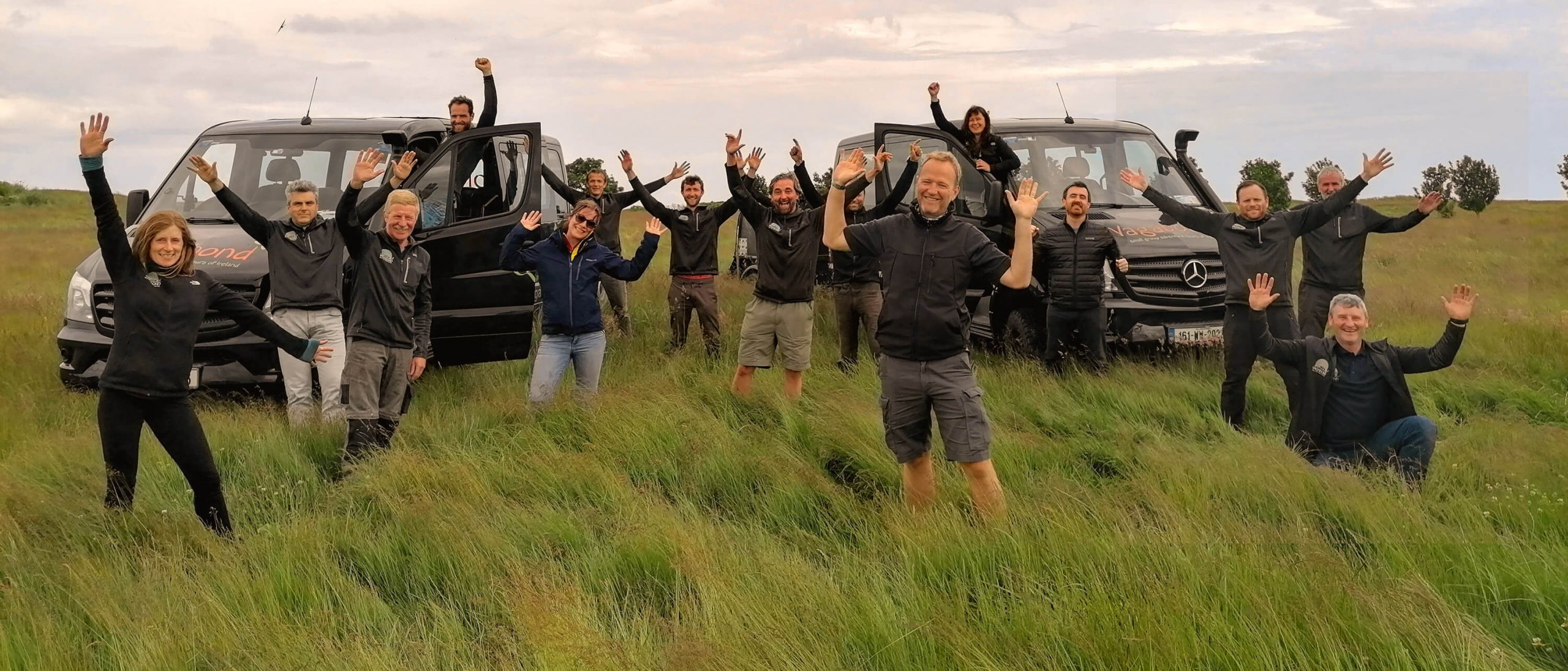 2022 Vagabond and Driftwood Ireland Tour Guide Team group posing in grass with tour vehicles